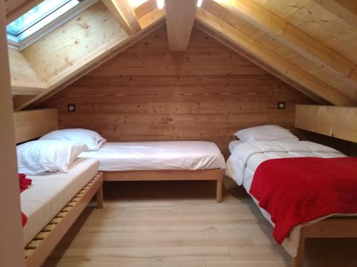 two beds in a attic room with wooden walls at Chalet des Lys - tout confort - 12 personnes in Valloire