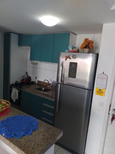 a stainless steel refrigerator in a kitchen with blue cabinets at Quartos - Cíntia in Fortaleza