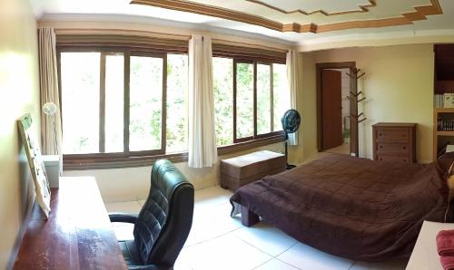 um quarto com uma cama, uma cadeira e janelas em Santuário na Chapad a dos Veadeiros em Alto Paraíso de Goiás