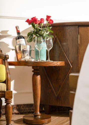 a table with wine glasses and a vase with flowers at Maison Fleur Luxury Hoi An in Hoi An