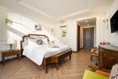 een slaapkamer met een groot wit bed en een tafel bij Maison Fleur Luxury Hoi An in Hội An