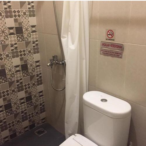 ein kleines Bad mit einem WC und einer Dusche in der Unterkunft Omah Joglo Pulau Merah in Pasanggaran