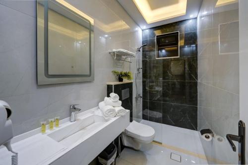 a bathroom with a sink and a toilet and a shower at Three Palms Suites in Aqaba