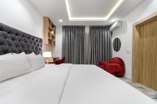 a bedroom with a large white bed and a red chair at W16 Water Front Apartments in Lekki