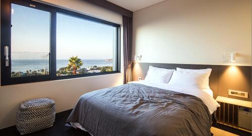 a bedroom with a large bed and a large window at Jeju Bricks Hotel in Seogwipo