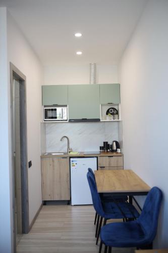 a kitchen with a wooden table and blue chairs at Tatents Toon Guesthouse in Gyumri