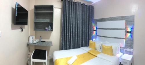 una camera da letto con un letto bianco con cuscini gialli di Mt. Everest Hotel a Kisii