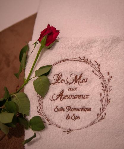a rose on a napkin with a flower on it at Le Mas aux Amoureux , Suite Romantique et Spa in Le Barcarès