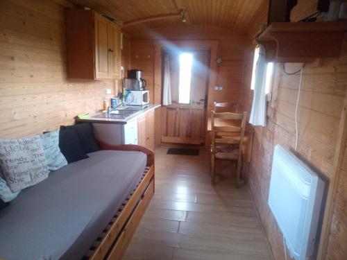 a small kitchen with a couch in a wooden cabin at Roulotte in Marnefer