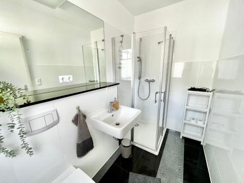 a white bathroom with a shower and a sink at Luxuriöse Doppelhaushälfte am grünen Rande von Hamburg in Oststeinbek