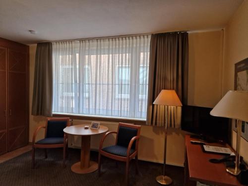 a hotel room with a table and chairs and a window at City Hotel Hanseatic Bremen in Bremen