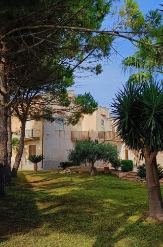 a building with trees in front of a yard at VersoSUD in Marsala