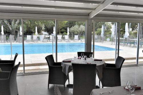 a dining room with a table and chairs and a pool at Le Domaine des Oliviers in Pierrelatte