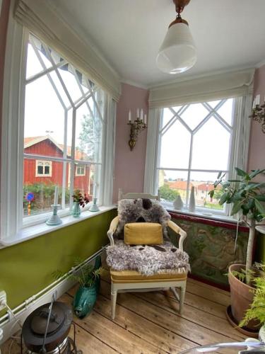 a room with a chair in a room with windows at Gränna Grandeur Stay in Style in Gränna