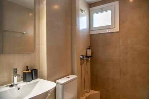 a bathroom with a sink and a toilet and a window at Zoe's cozy room 1 in Artemida