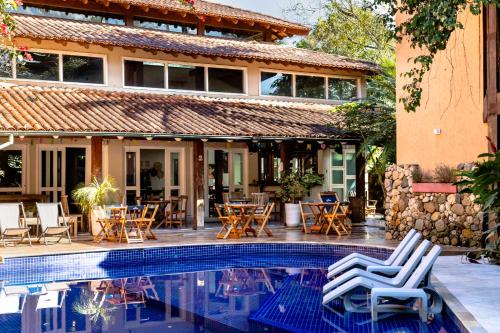 a resort with a pool and chairs and tables at Pousada Camburizinho in Camburi