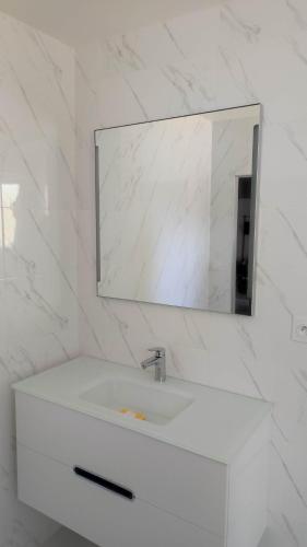 une salle de bain blanche avec un lavabo et un miroir dans l'établissement La maison d'Elise, à Solesmes