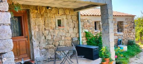 Petreto-BicchisanoにあるCasa Di Minnanaの木製のドアとテーブルと椅子が備わる石造りの家