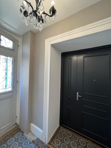 a black door in a room with a chandelier at La Cour du Prince in Verdun