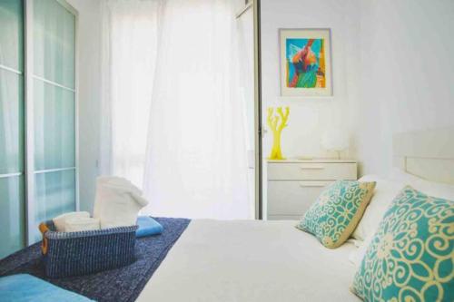 a bedroom with a white bed with blue pillows at Terrazza Sul Mare by Le Dhome Sicily in Trappeto