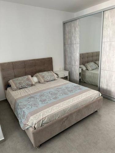 1 dormitorio con 1 cama grande y espejo en Appartement Guivat Olga 4 pièces proche mer, en H̱adera