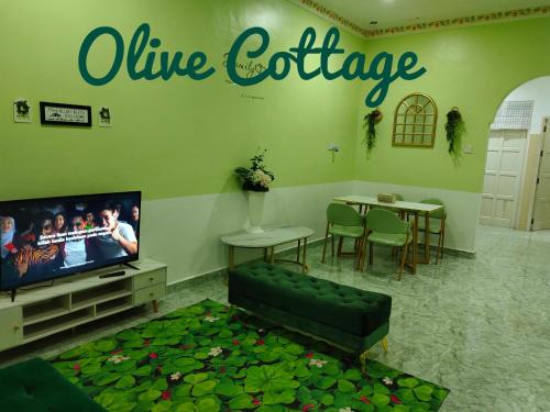 a living room with a couch and a tv and a table at Olive Cottage in Kampong Ru Lima