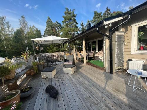 a wooden deck with chairs and a table and an umbrella at Ingarö Brudbergsvägen 17 in Stockholm