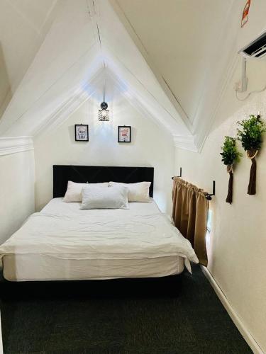 a bedroom with a white bed with two plants on the wall at Abe.Cottage 2 in Kampung Kuala Besut