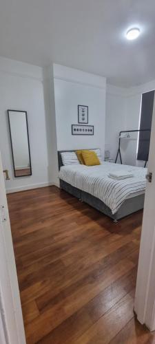 um quarto com uma cama e piso em madeira em Cricklewood Broadway Guest Home em Londres