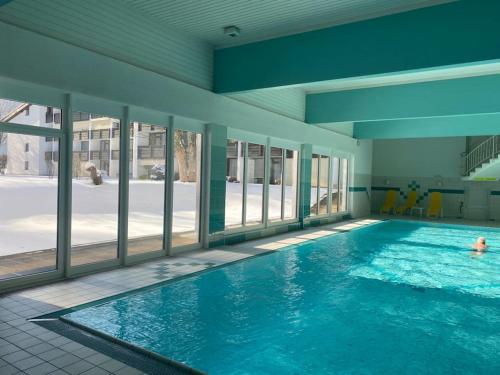 a large swimming pool with blue water in a building at Stylisches Chalet im Schlosspark Grubhof mit Innenpool und Balkon in Sankt Martin bei Lofer