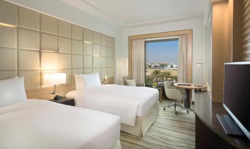 um quarto de hotel com duas camas e uma televisão em DoubleTree by Hilton Hotel Riyadh - Al Muroj Business Gate em Riyadh