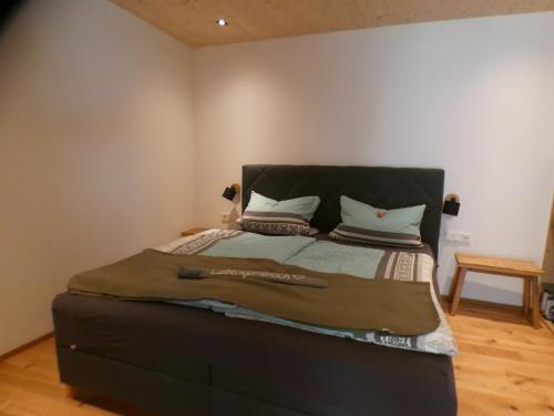 a bed with a black headboard in a room at Stylische Fewo in Bestlage in neugebautem Holzhaus mit Oberstaufen Plus in Oberstaufen