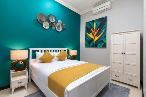 1 dormitorio con cama y pared azul en SUNNYRENT. Green villa for family rest in Nusa Dua, en Nusa Dua