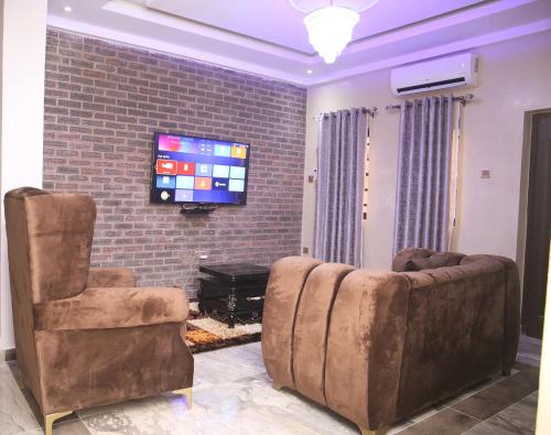 a living room with two chairs and a flat screen tv at Newly Built 2 Bedroom Tastefully Furnished House Available For Shortlet. in Lagos