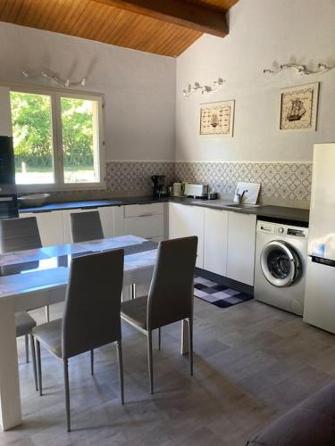 une cuisine avec une table et des chaises ainsi qu'un lave-linge dans l'établissement charment logement avec piscine et jardin, à Baurech