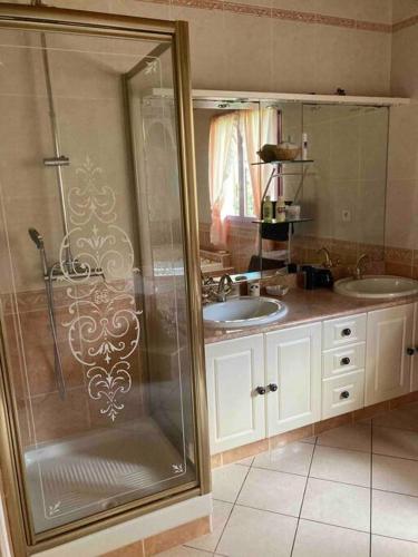une salle de bain avec deux lavabos et une douche en verre dans l'établissement charment logement avec piscine et jardin, à Baurech