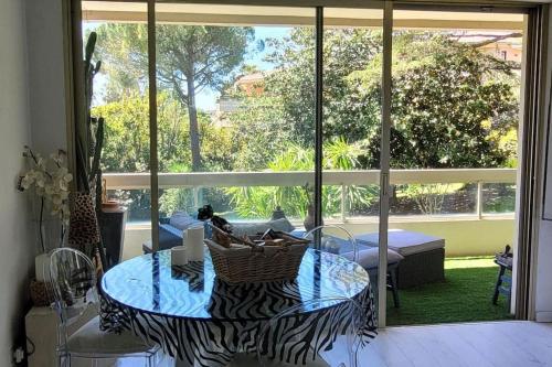 un salon avec une table et une grande fenêtre dans l'établissement Cannes centre beau 2 pièces 50 M2 plus terrasse à 12 min plages et Palais au calme, à Cannes