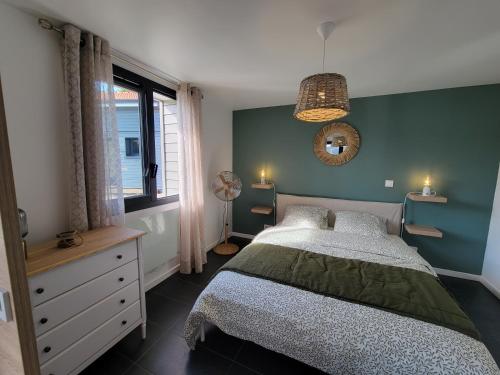 a bedroom with a bed and a green wall at Les Cabanes de l'Airial Ecume in Andernos-les-Bains