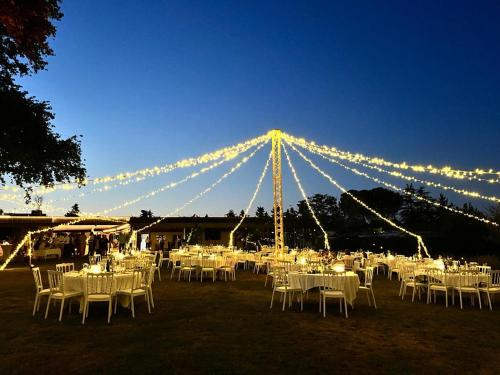 a group of tables with white chairs and lights at ORANGERIE de CHATEL-Selection FIGARO & ELLE Magazine in Cleppé