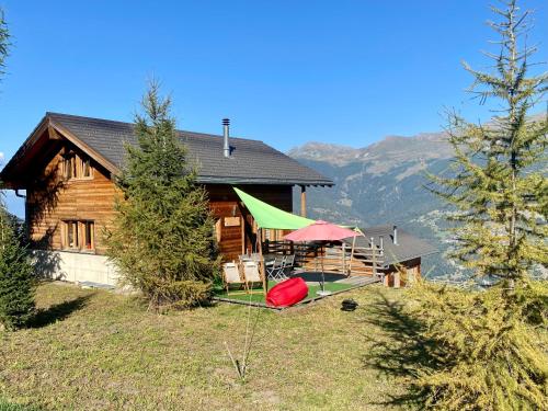 una casa de madera con mesas y sombrillas delante en La Pourvoirie - 4 Vallées - Thyon-Les Collons, 10 personnes, pistes de ski à 200m, magnifique vue, en Hérémence