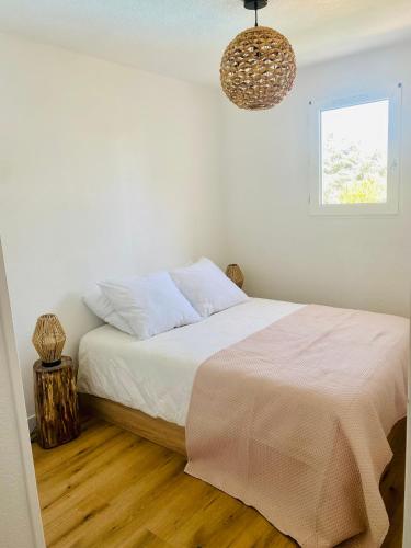 - une chambre blanche avec un lit et un lustre dans l'établissement Appartement avec piscine 500m de la plage de Pontaillac, à Vaux-sur-Mer