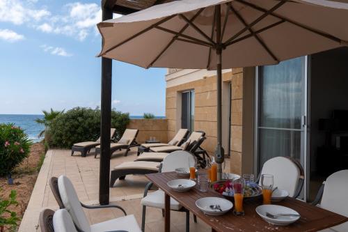 a patio with tables and chairs and an umbrella at True front line apartment in Tatlisu North Cyprus in Küçükerenköy