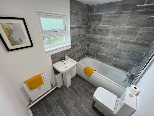 a bathroom with a white tub and a sink at 2 Bedroom Flat, Free Parking & Wi-Fi in Haversham