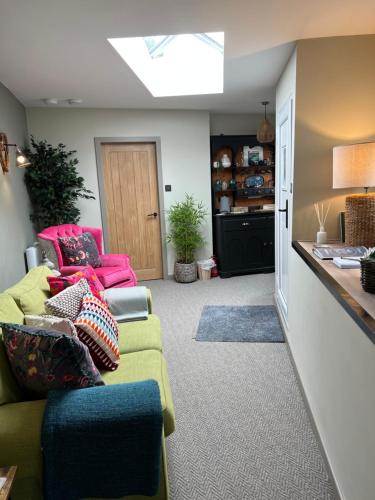 a living room with a green couch and pink chairs at Luxury Cottage in Tregarth, Bethesda, Snowdonia in Tregarth