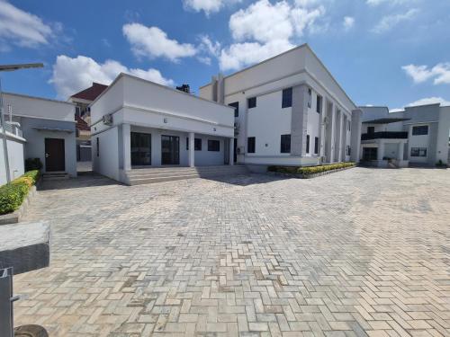 a large white building with a brick driveway at Solace Suites and Homes Maiduguri in Maiduguri