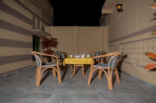 a table and chairs on a porch with a yellow table and chairs at Hotel white season Gulberg in Lahore