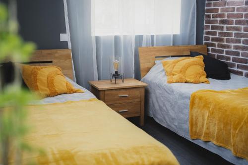 a bedroom with two beds with yellow pillows and a brick wall at MaxiMar Apartment With Sauna in Valga