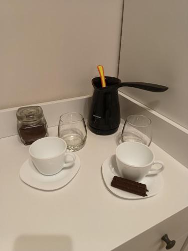 two cups and saucers on a counter with glasses at Chechar Inn Zlatar in Nova Varoš