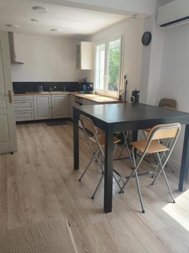 een keuken met een zwarte tafel en 2 stoelen bij Appartement F4 Le Milena in Saint-Paul-et-Valmalle