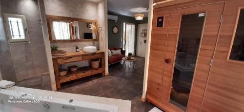 uma casa de banho com uma banheira, um lavatório e um espelho. em Le Mas aux Amoureux , Suite Romantique et Spa em Le Barcarès